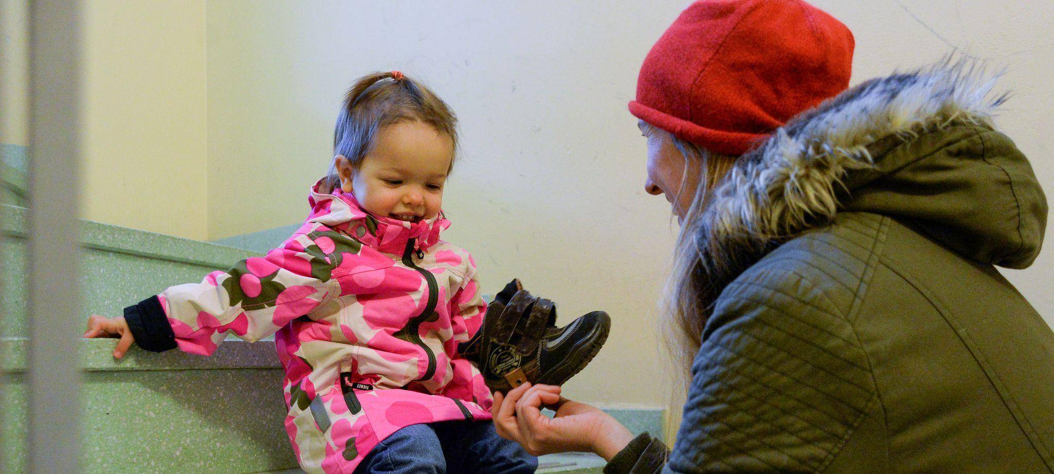 Eine Mutter hilft einem Kleinkind die Schuhe anzuziehen