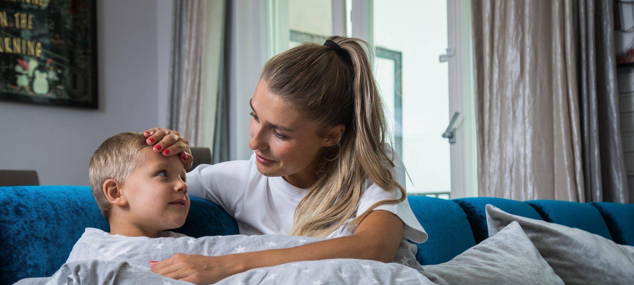 Eine Mutter legt ihre Hand auf die Stirn ihres Sohnes