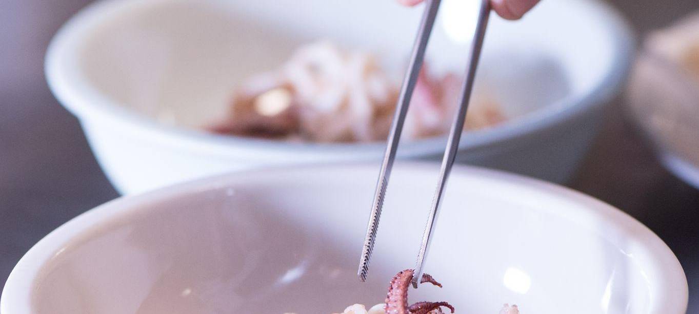 Koch richtet mit einer Pinzette ein Gericht an