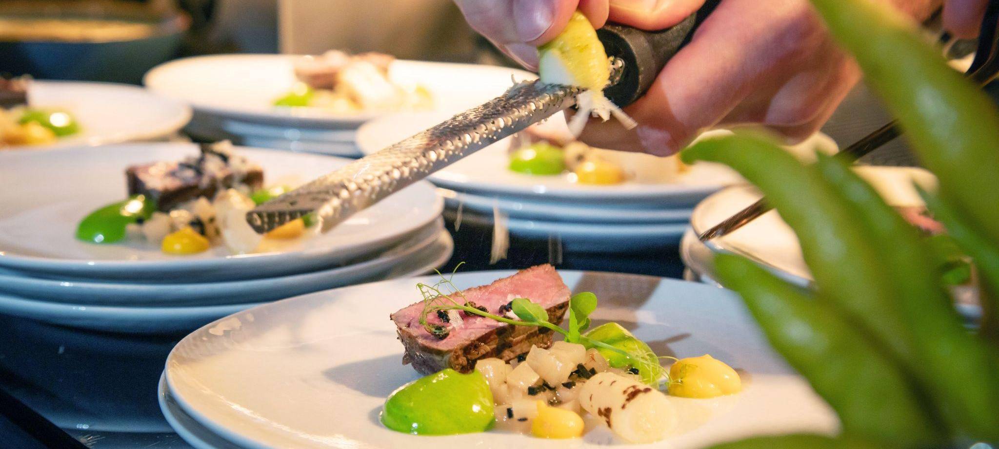 Koch reibt Zesten der Zitrusfrucht Buddhas Hand über ein Menü