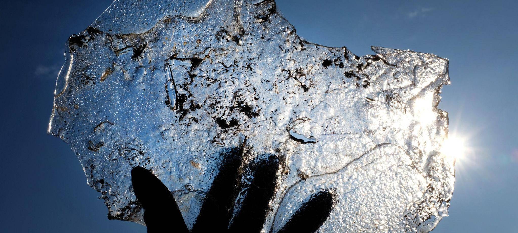 Eine Hand hält eine Eisplatte vor blauem Himmel