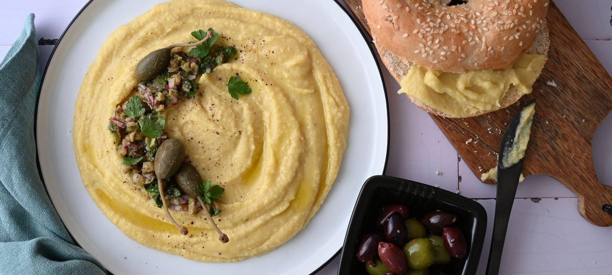 Ein Teller Linsendip, ein Bagel und eine Schale Oliven