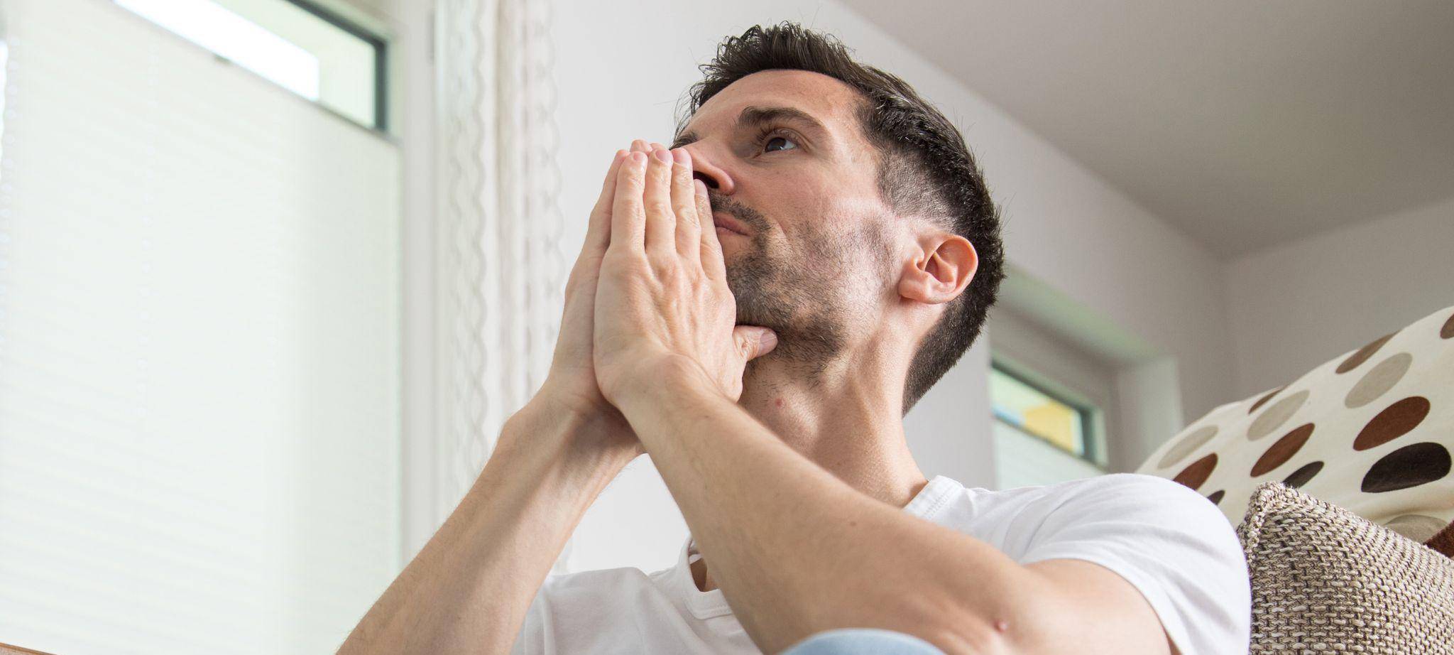 Mann sitzt nachdenklich im Wohnzimmer