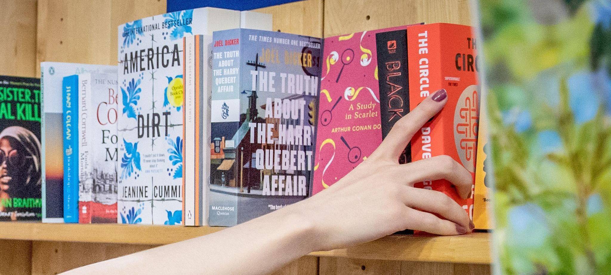 Eine Frau entnimmt ein Buch aus einem Regal