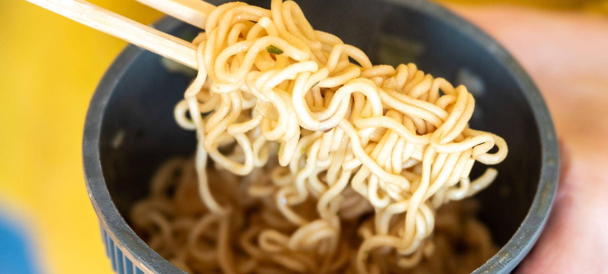 Eine Frau hält einen Becher Instantnudeln in der Hand