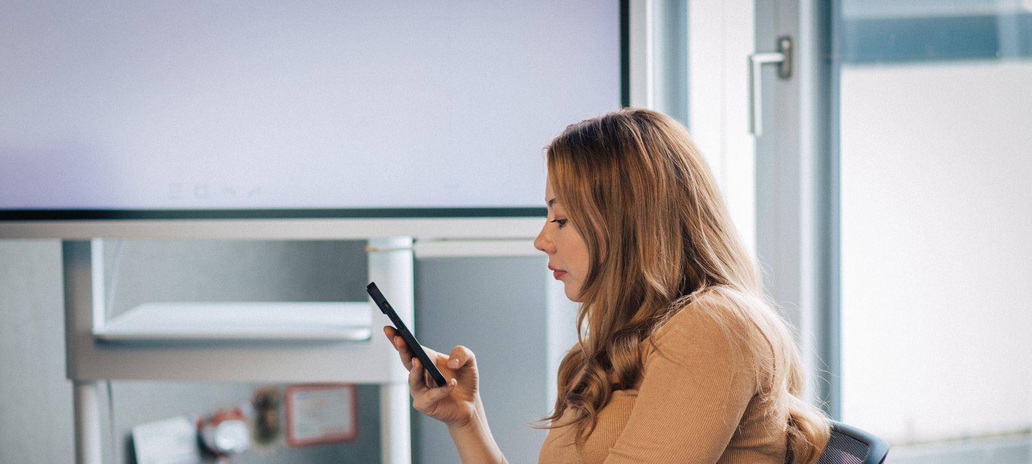 Junge Frau mit Smartphone im Büro