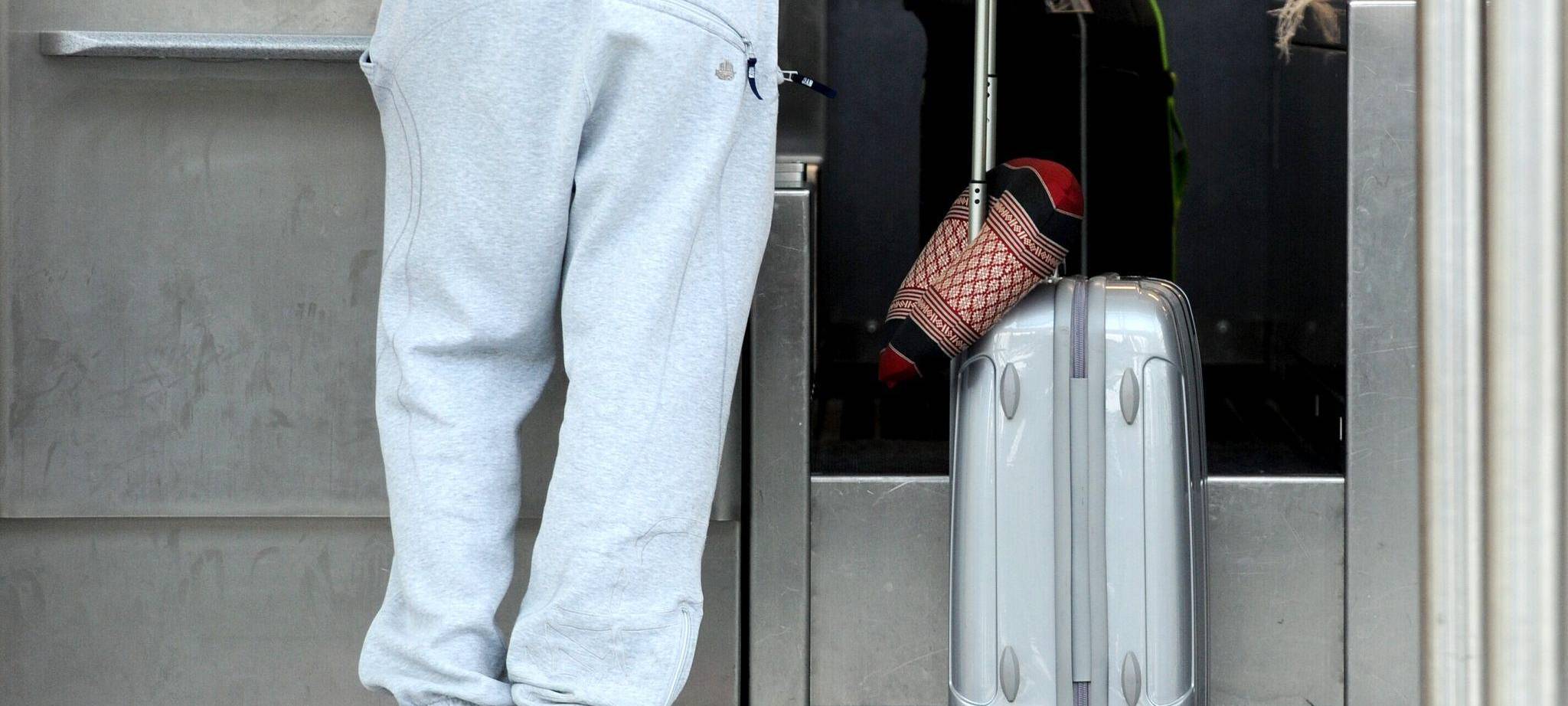 Ein Passagier in Jogginghose steht bei der Gepäckabgabe