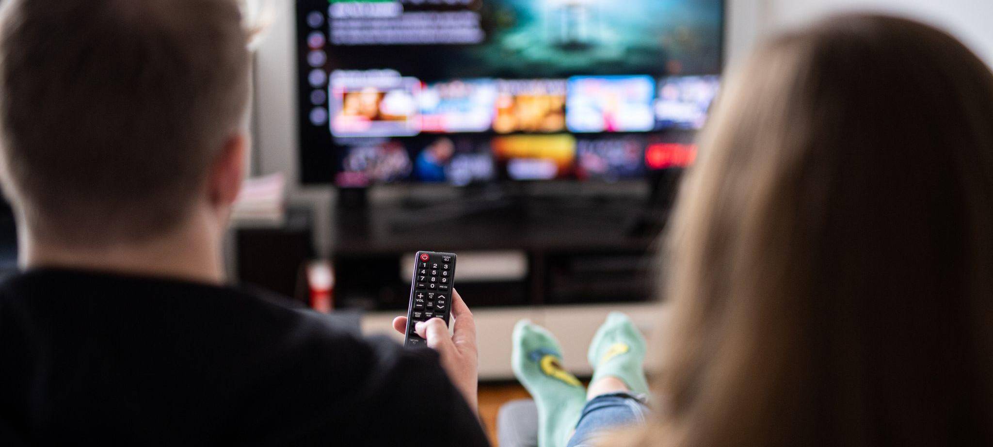 Paar sitzt vor einem Fernseher mit Streamingdiensten