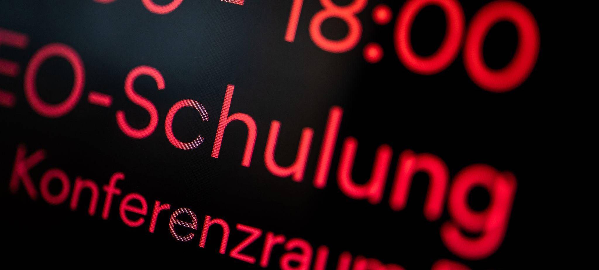 Digitale Anzeige an einem Konferenzraum weist auf Schulung hin