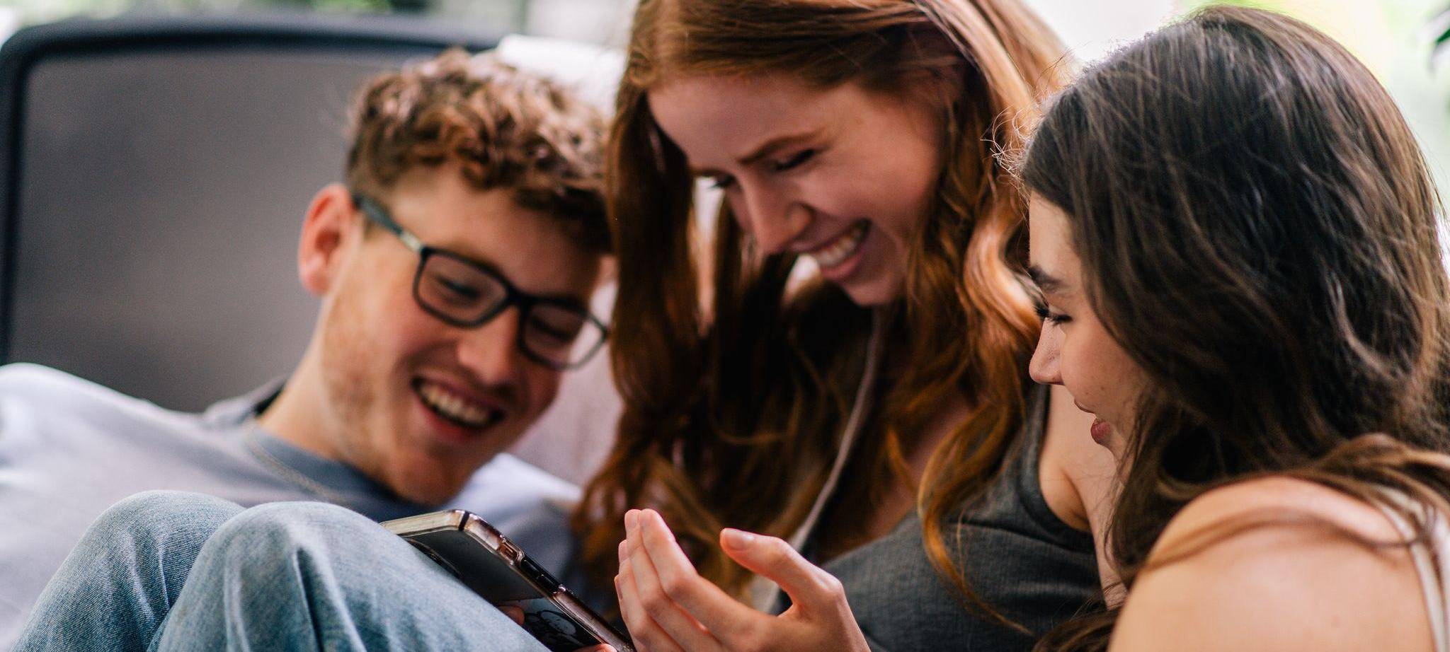 Drei Freunde schauen gemeinsam aufs Handy