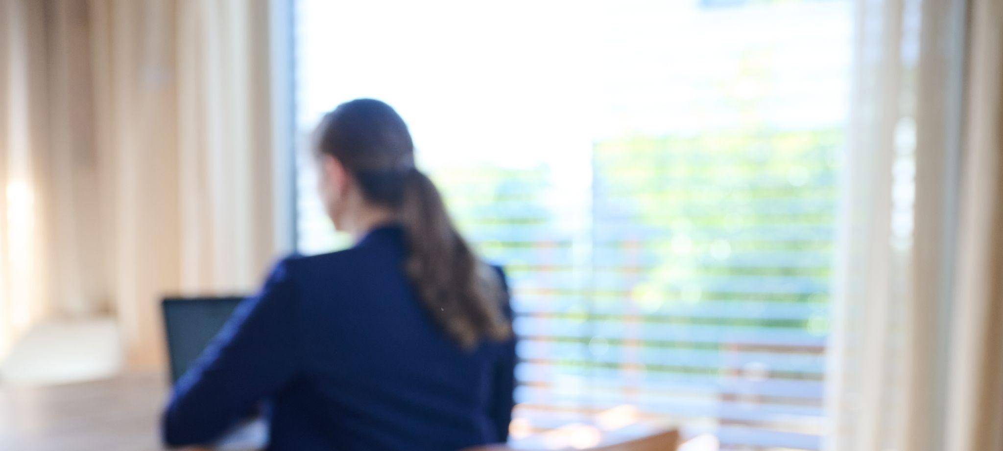 Smartphone auf einem Tisch, im Hintergrund arbeitet eine Frau