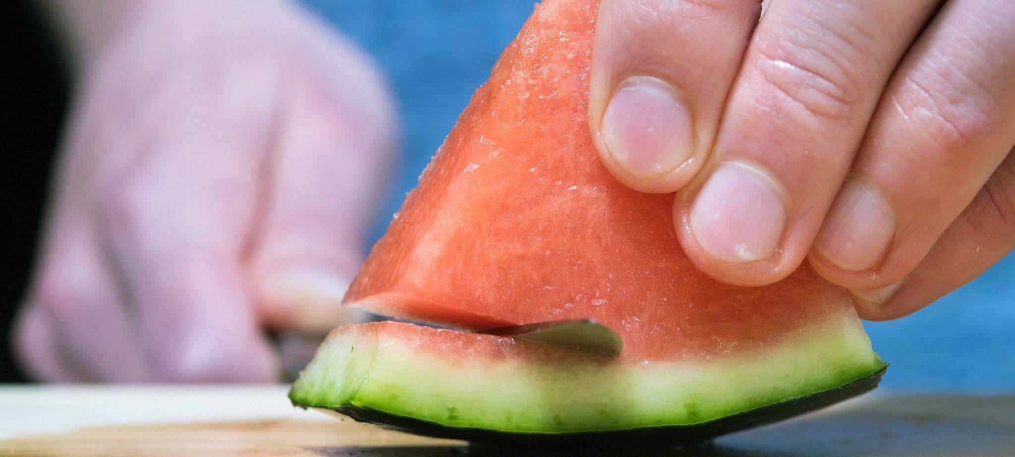 Mann schneidet eine Wassermelone