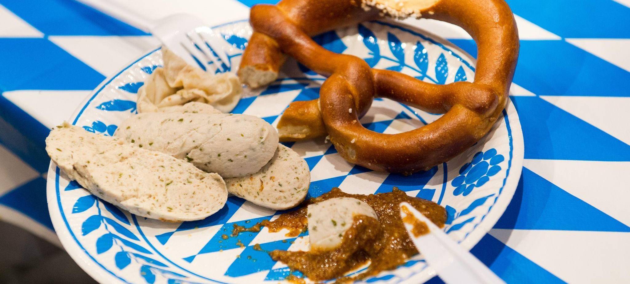 Eine Weisswurst und eine Brezel liegen auf einem Teller