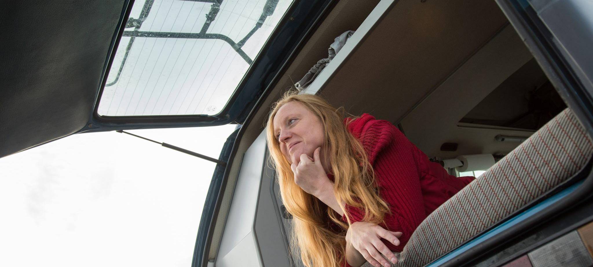 Eine Frau liegt auf dem Bett eines Campervans