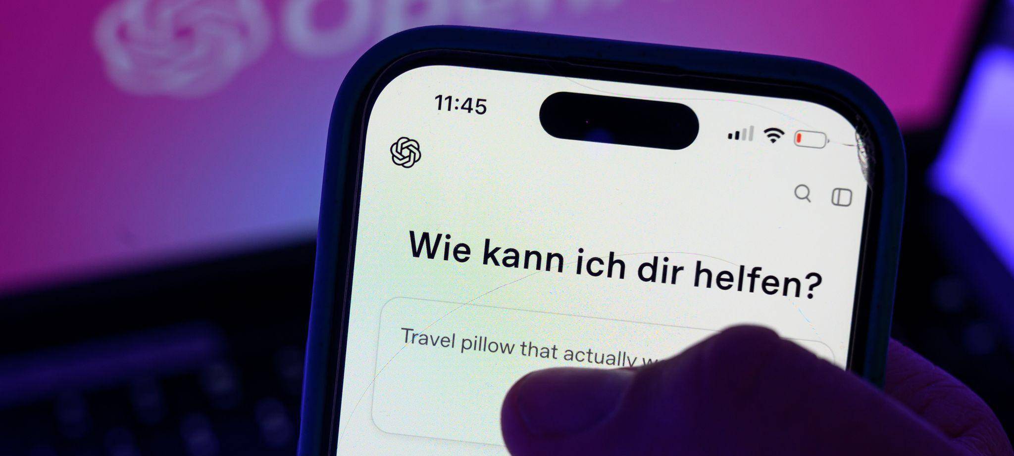 Smartphone mit dem KI-Chatbot ChatGPT vor dem Logo von OpenAI
