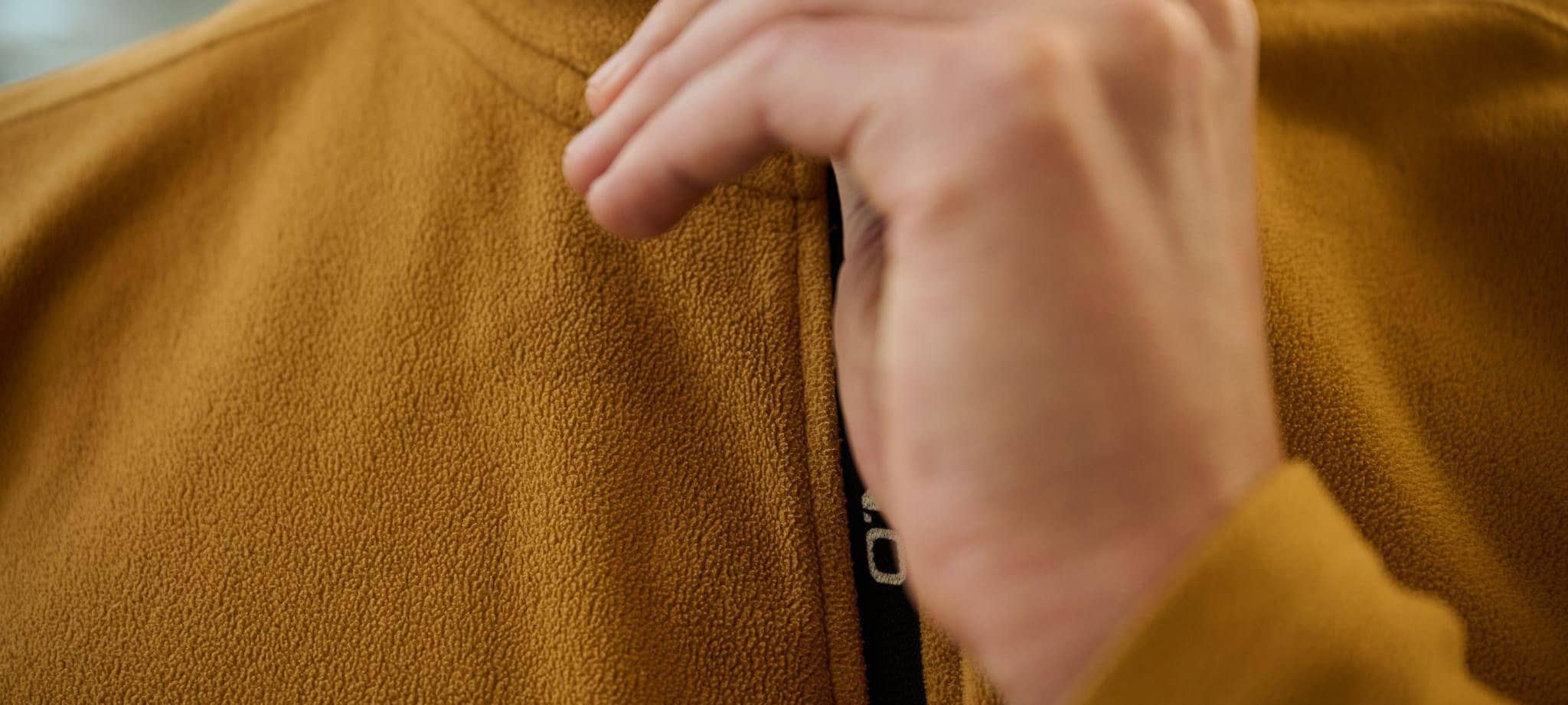 Ein Mann schließt den Reißverschluss einer Fleecejacke