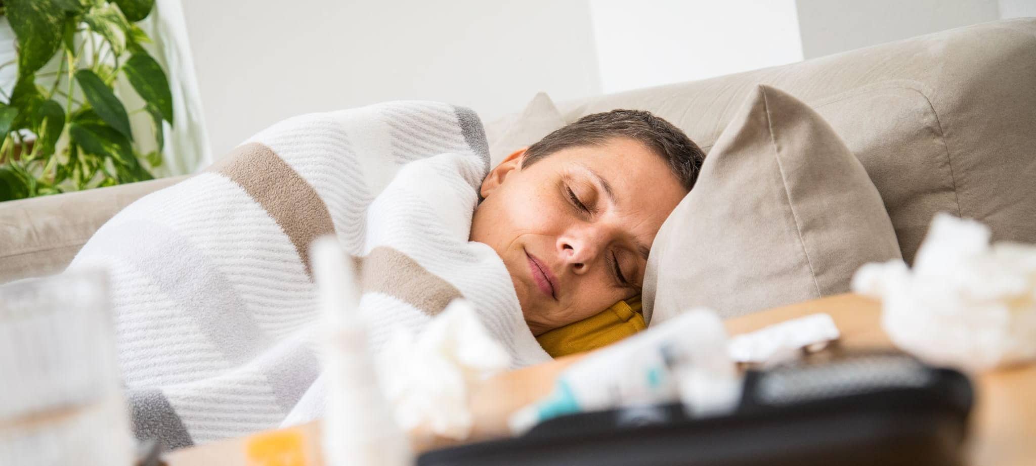 Eine Frau liegt krank auf einem Sofa