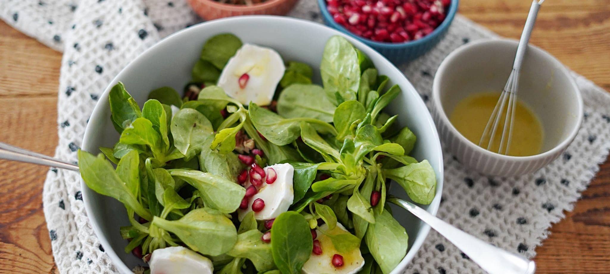 Schüsseln mit Feldsalat und Granatapfelkernen auf einem Tisch